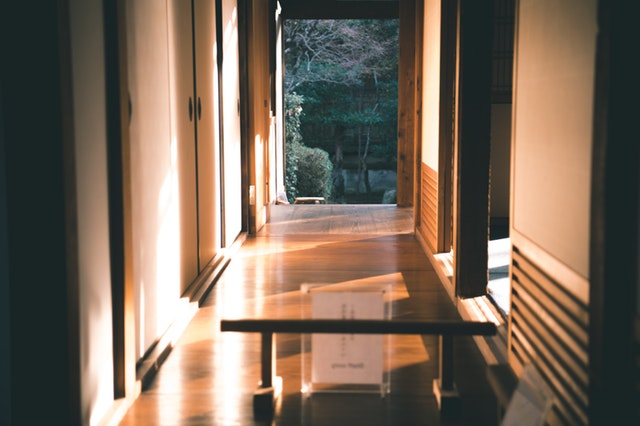 Pohľad cez sklenené dvere na úzku chodbu obloženú drevom vedúcu do záhrady