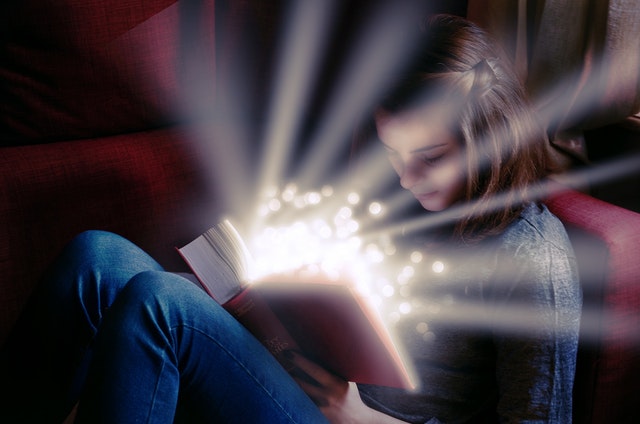 Dievča číta knihu, z ktorej vyžaruje svetlo.jpg